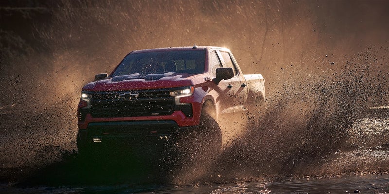 Red Chevrolet Silverado 1500 drifting off-road.